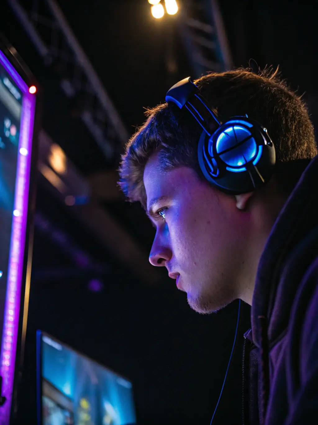 A professional gamer intensely focused on their screen during a high-stakes eSports tournament, bathed in the glow of gaming monitors, showcasing the dedication and skill involved in professional game coaching.